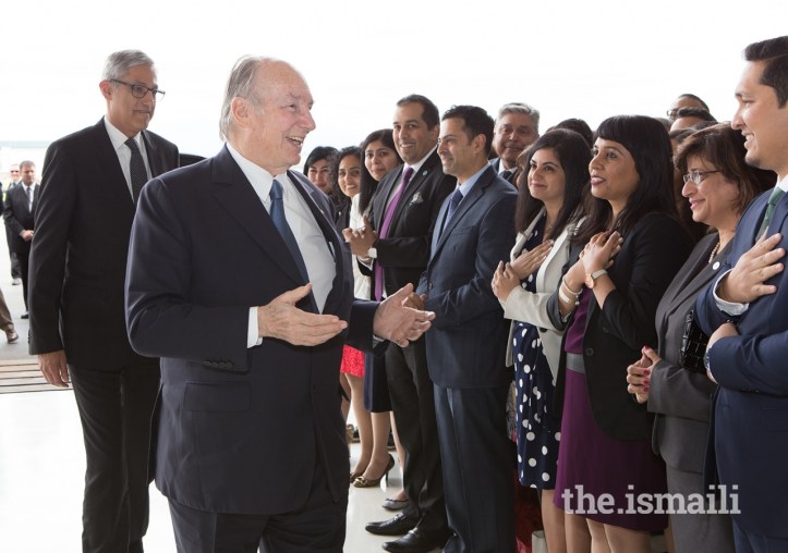 Aga Khan IV greeting members of the Ismaili community during a visit, with individuals expressing respect by placing their hands on their hearts.
