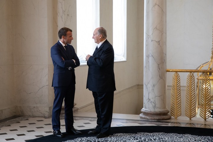 Aga Khan speaking with French President Emmanuel Macron in an elegantly decorated interior space.