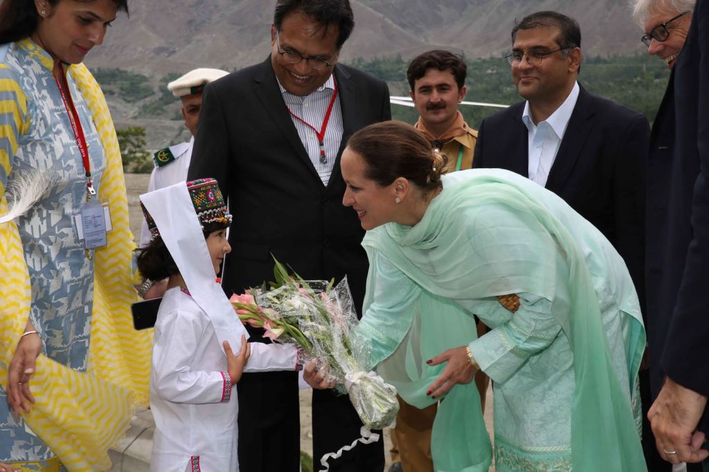 Princess Zahra Aga Khan greeting a young girl dressed in traditional attire, handing her flowers during a visit in a mountainous region.