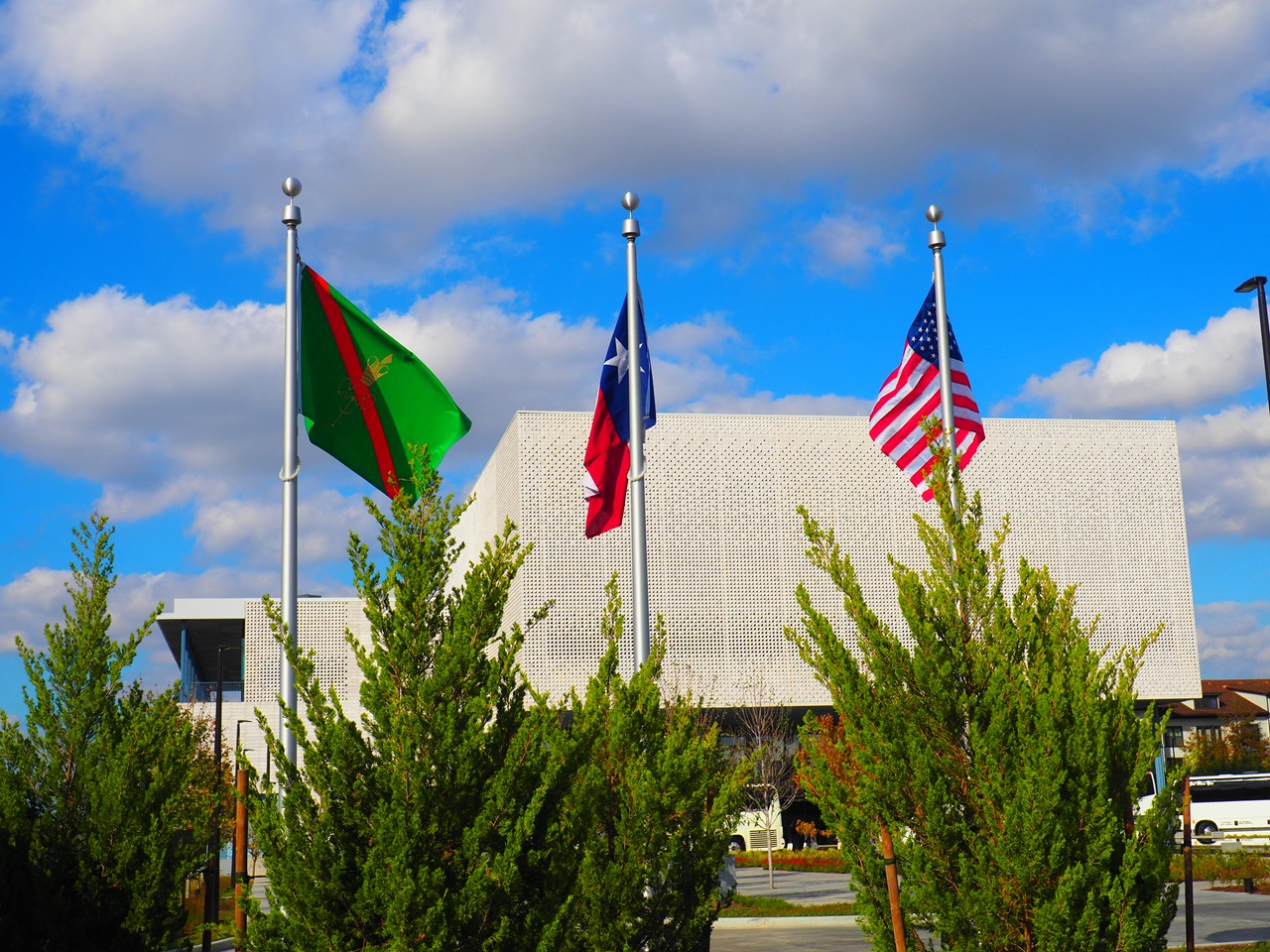 Flags of the USA, the State of Texas and the Ismaili Imamat bearfing the crest of the Imam, fly in the south garden, near the Montrose Avenu Gate of the Ismaili Center, Houston
