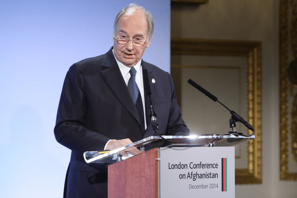 Aga Khan IV delivering a speech at the London Conference on Afghanistan in December 2014, standing behind a podium with a sign indicating the conference theme.