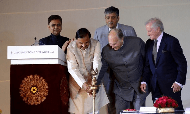 A group of individuals participating in a ceremonial event at the Humayun's Tomb Site Museum, with one person lighting a traditional lamp.